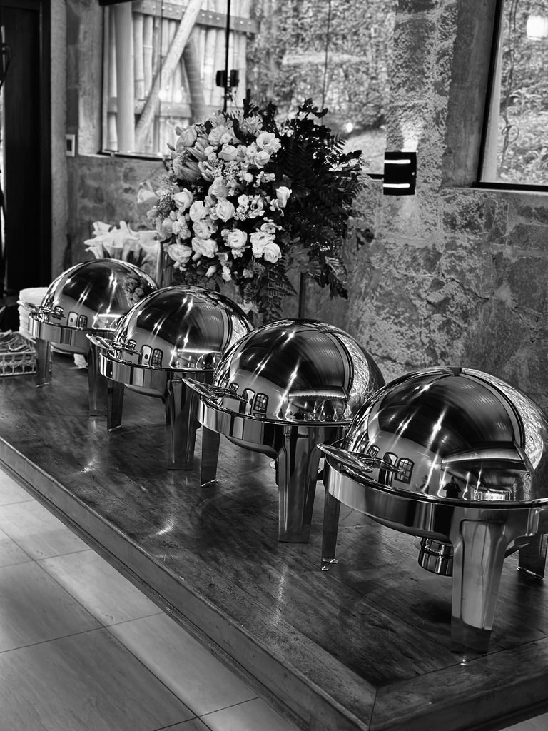 Buffet Emerick Eventos — réchauds em mesa de madeira com arranjo de flores